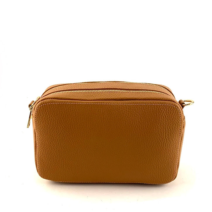 Tan pebbled leather crossbody bag with dual gold zipper compartments and contrast stitching on white background