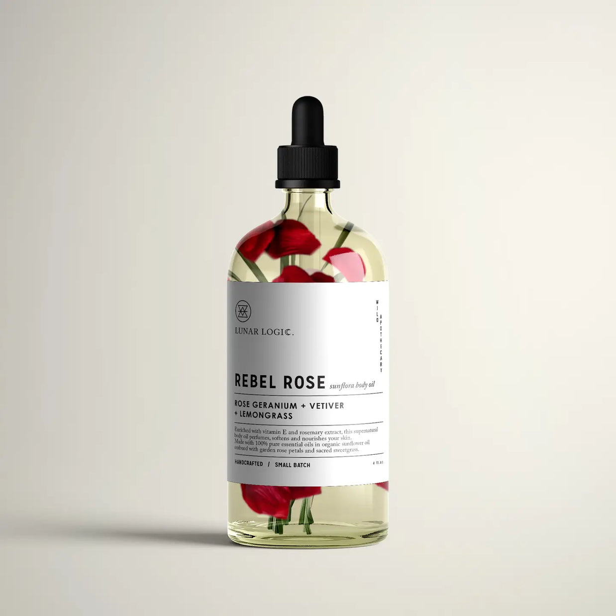 Clear glass bottle with black dropper cap containing golden oil with red rose petals and pink flowers, white labeled Rebel Rose