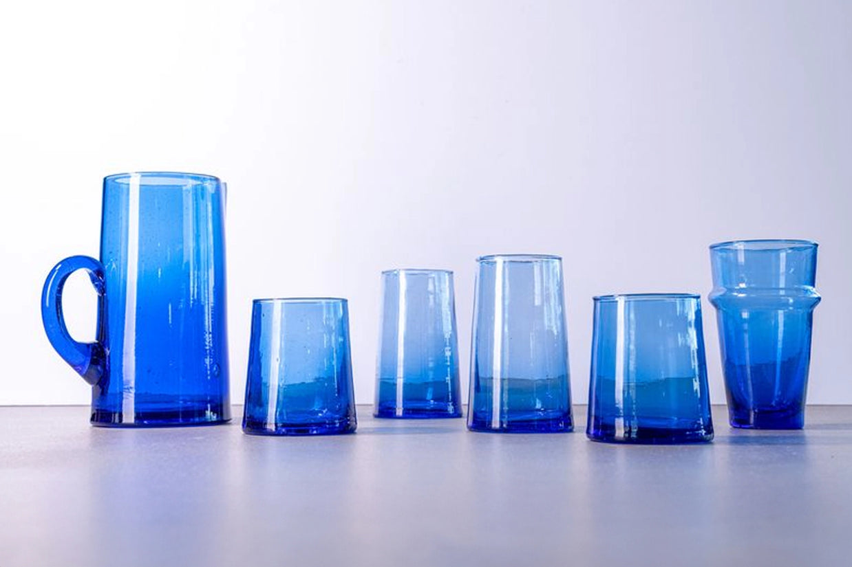 Cobalt blue glass drinkware set with faceted geometric sides including tall pitcher with handle and five varying tumblers
