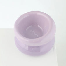 Elevated ceramic pet bowl in soft lavender with embossed brand name on interior and wide stable base on white surface