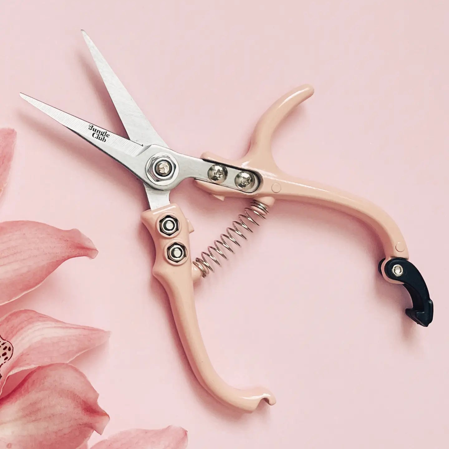 Pink-handled scissors with silver blades on a pink background with floral elements