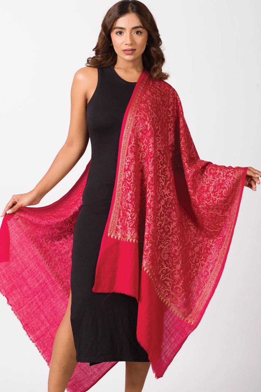 Red wool shawl with intricate gold paisley embroidery and scalloped edges draped over model wearing black dress