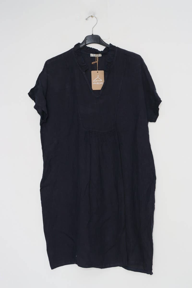 Black linen shift dress with ruffled neckline, rolled short sleeves, and relaxed fit hanging on hanger with tan tag