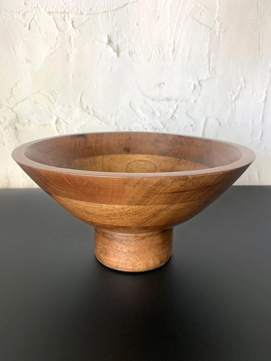 Hand-turned wooden pedestal bowl in warm honey-toned wood with visible grain patterns and cylindrical footed base