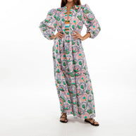 Pink maxi dress with green and turquoise paisley print, puffed sleeves, V-neckline with striped trim, and flowing skirt