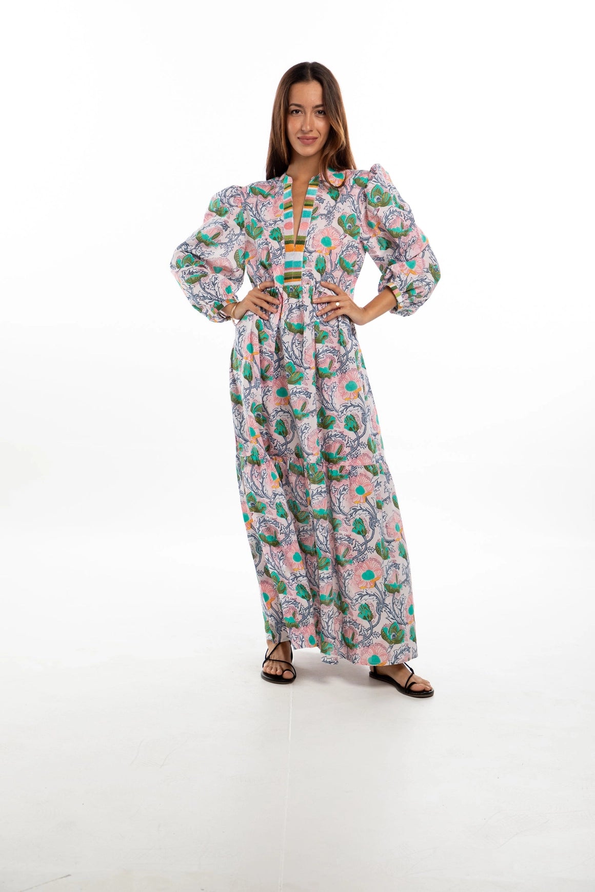 Pink maxi dress with green and turquoise paisley print, puffed sleeves, V-neckline with striped trim, and flowing skirt