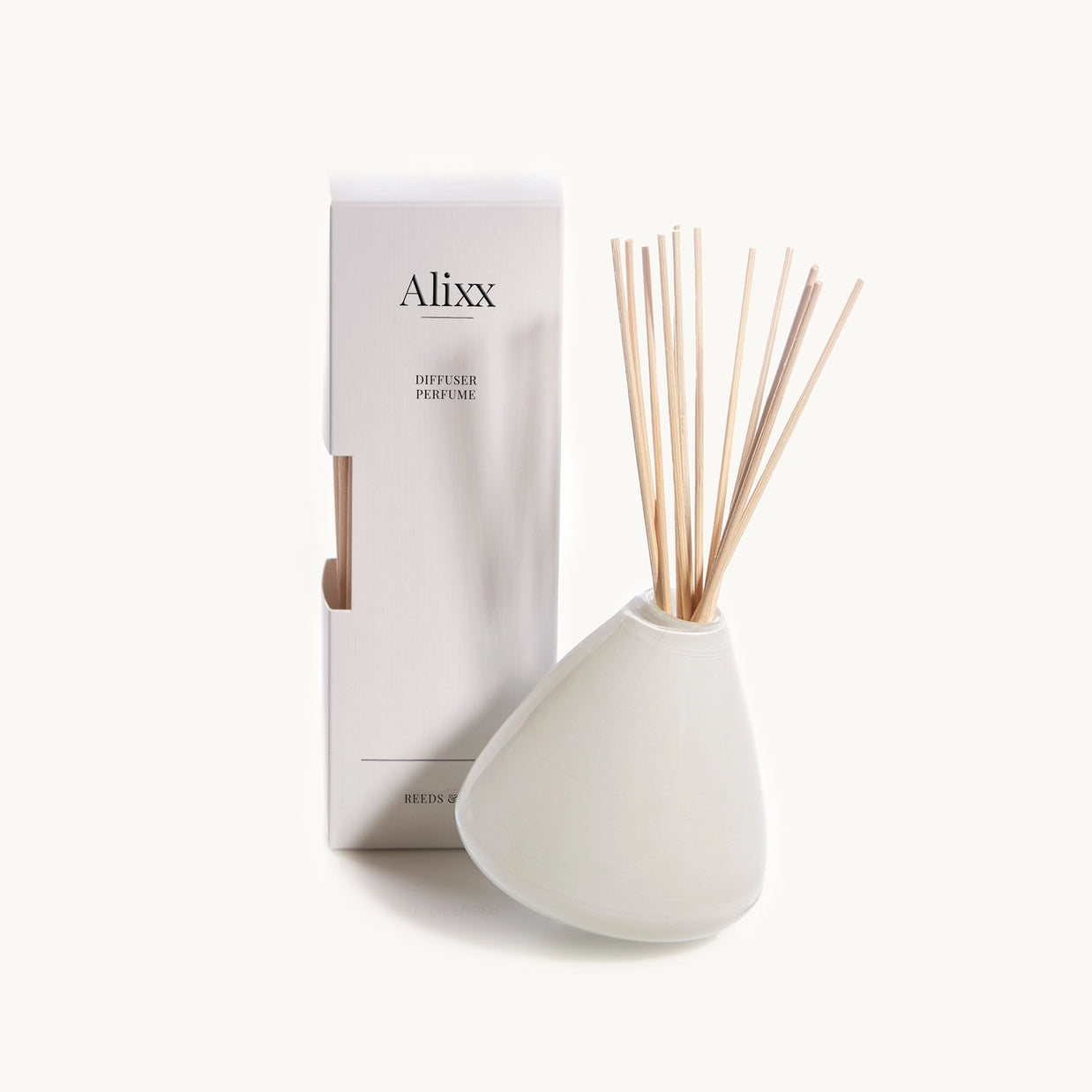 White ceramic teardrop-shaped reed diffuser with natural bamboo sticks beside matching Alixx branded packaging box