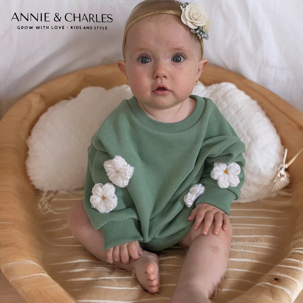 Sage green baby sweatshirt with white crochet daisy appliqués on sleeves and ribbed crew neckline and cuffs