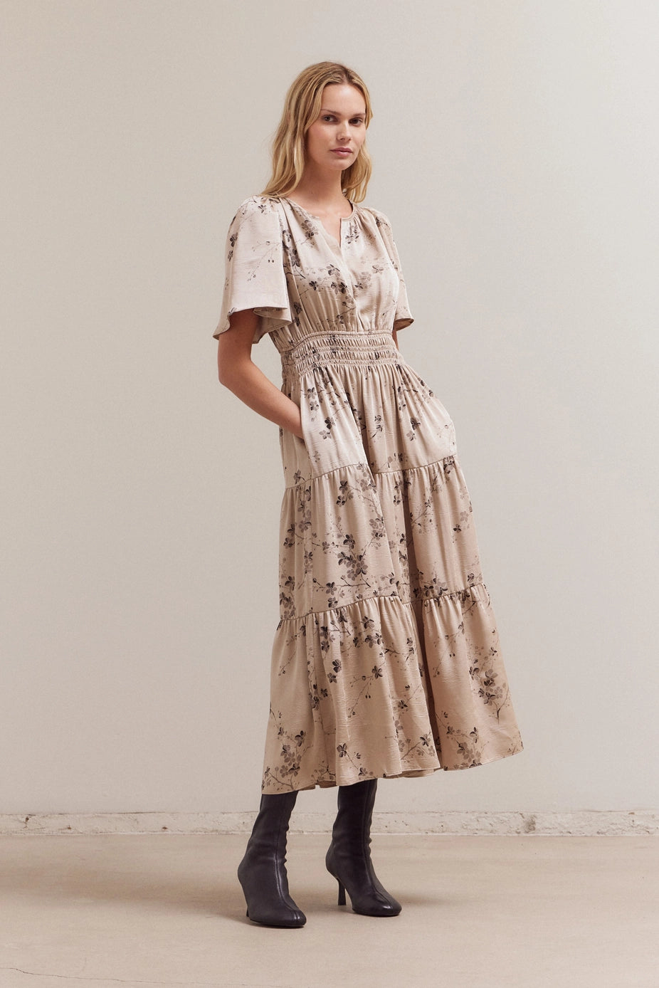 Beige floral midi dress with smocked waist, flutter sleeves, tiered ruffle skirt, and brown botanical print pattern