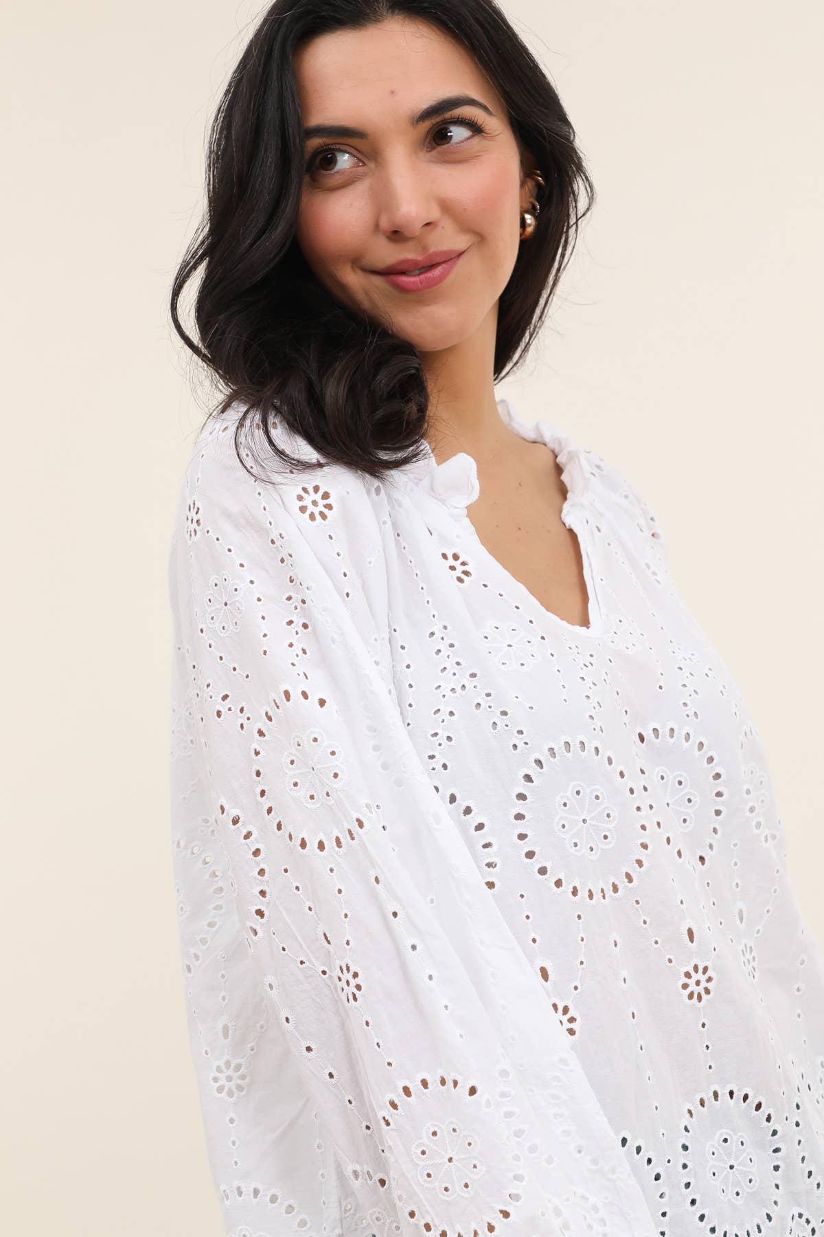 White cotton eyelet lace tunic with circular floral cutout pattern, ruffled V-neckline and three-quarter sleeves