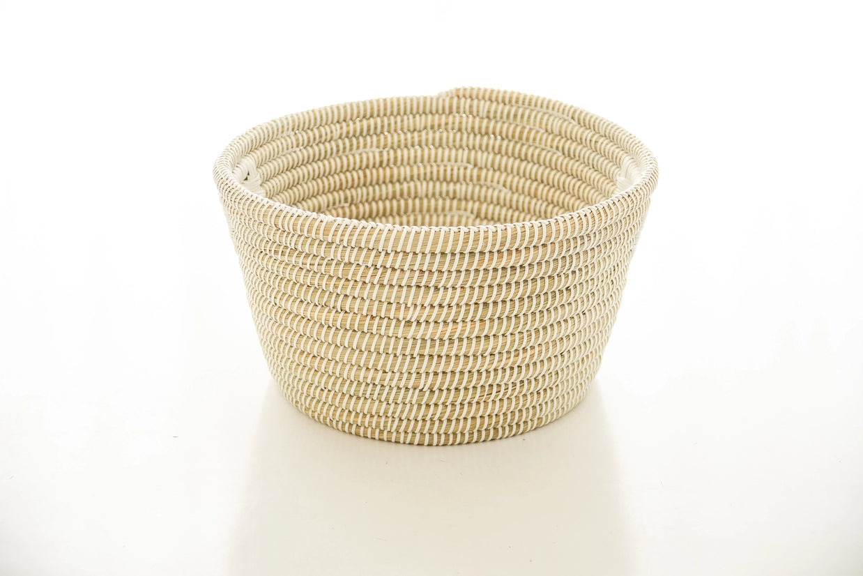 Hand-woven round basket in natural tan and white kaisa grass with tight coiled pattern and wide rimmed opening