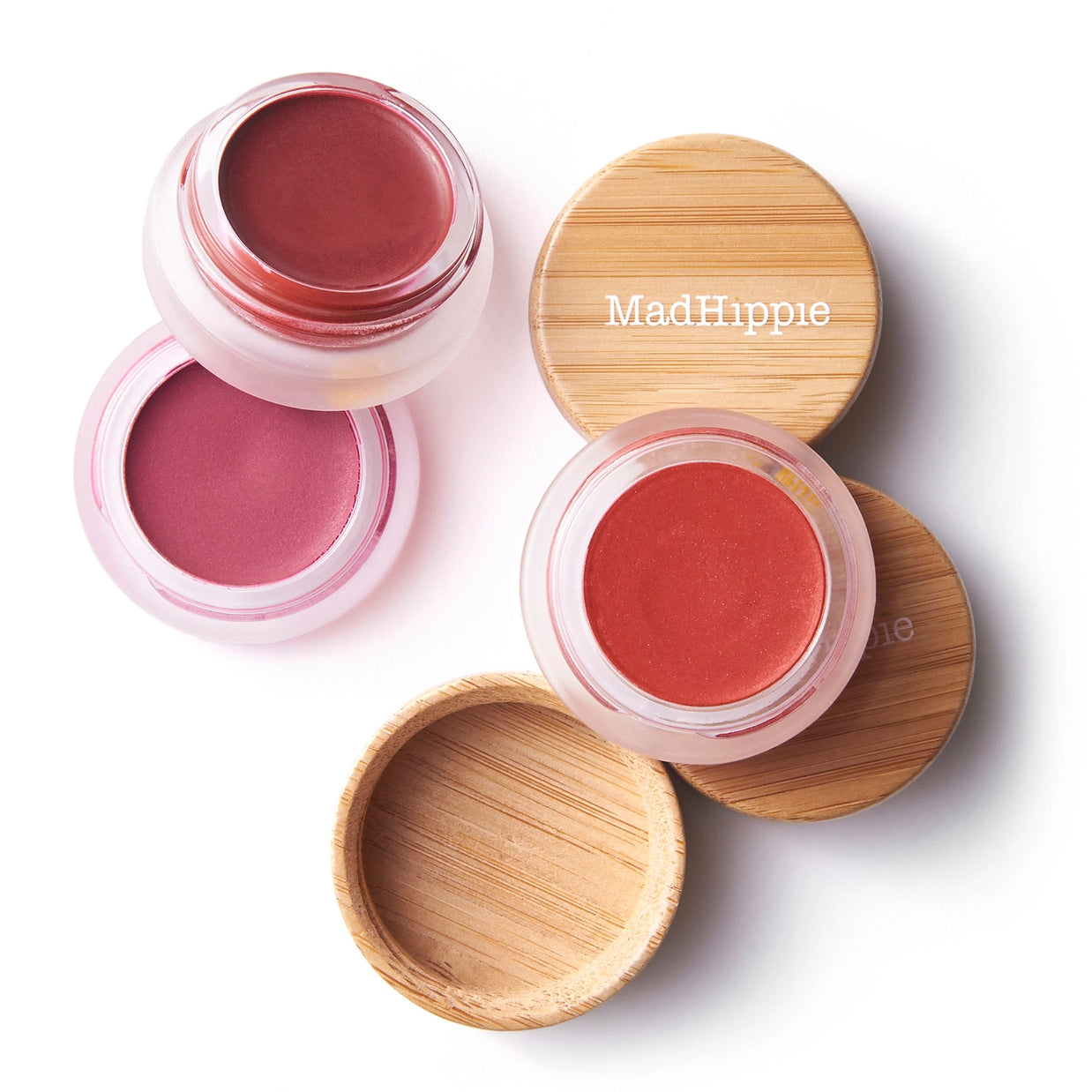 Cream blush and lip tint in mauve-pink and coral-red shades with bamboo lids and clear pink containers on white background