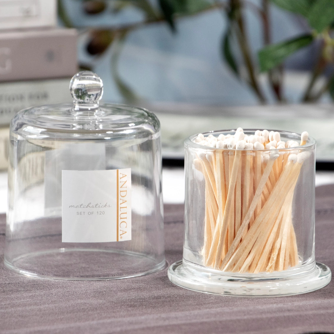 Clear glass apothecary jar with dome lid holding wooden matchsticks with white tips on marble countertop