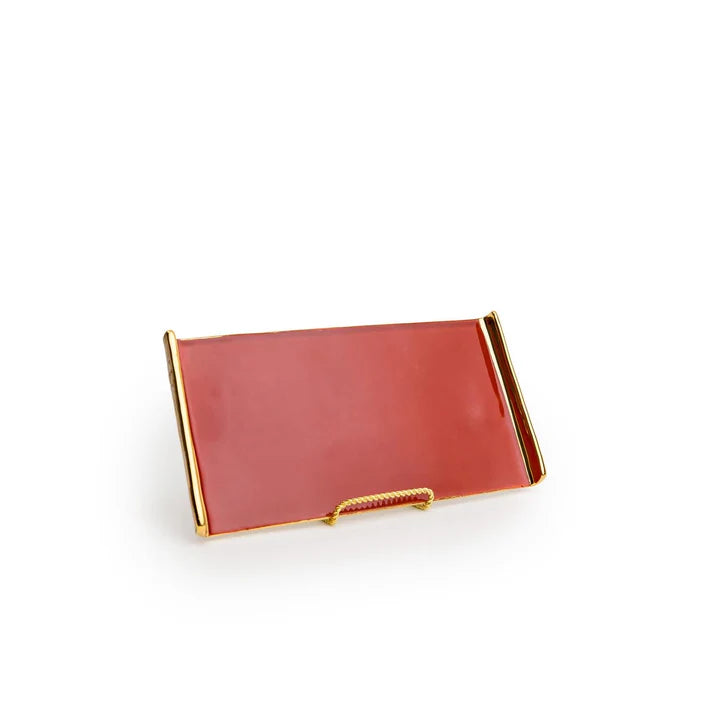 Coral pink glass tray with polished gold metal handles and decorative gold rope detail on white background