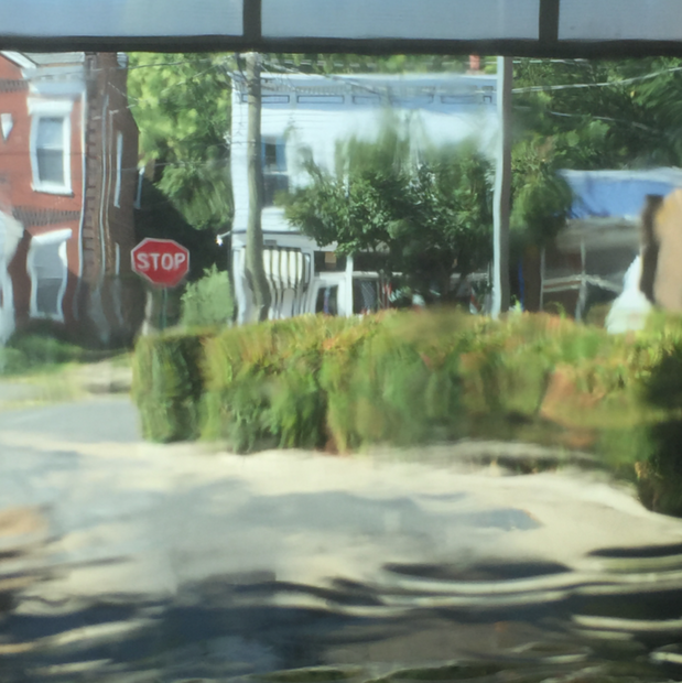 A metal print featuring an impressionist scene with a stop sign, trees, and a building in the background.
